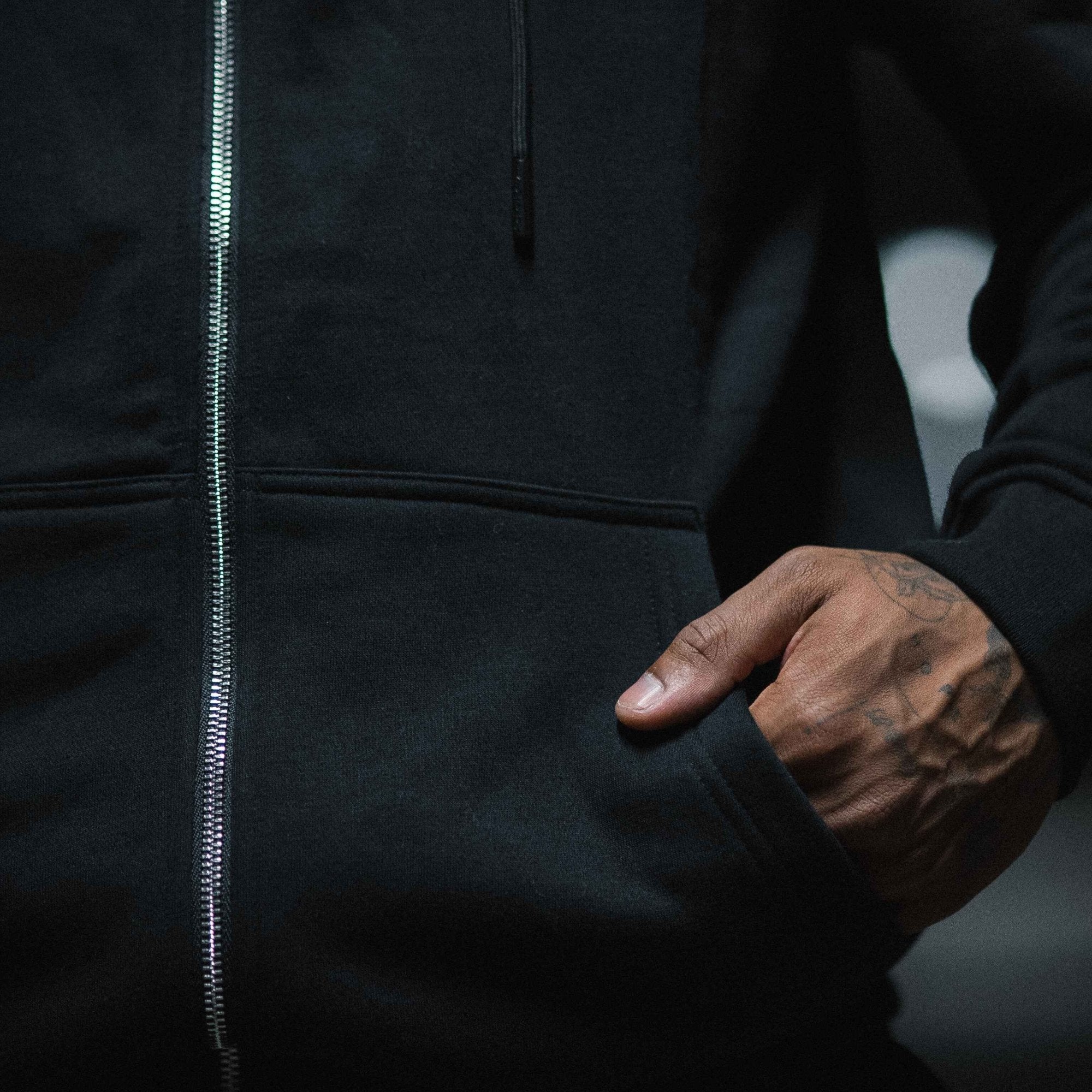 Ascend zip up black white with hand in front pocket close up